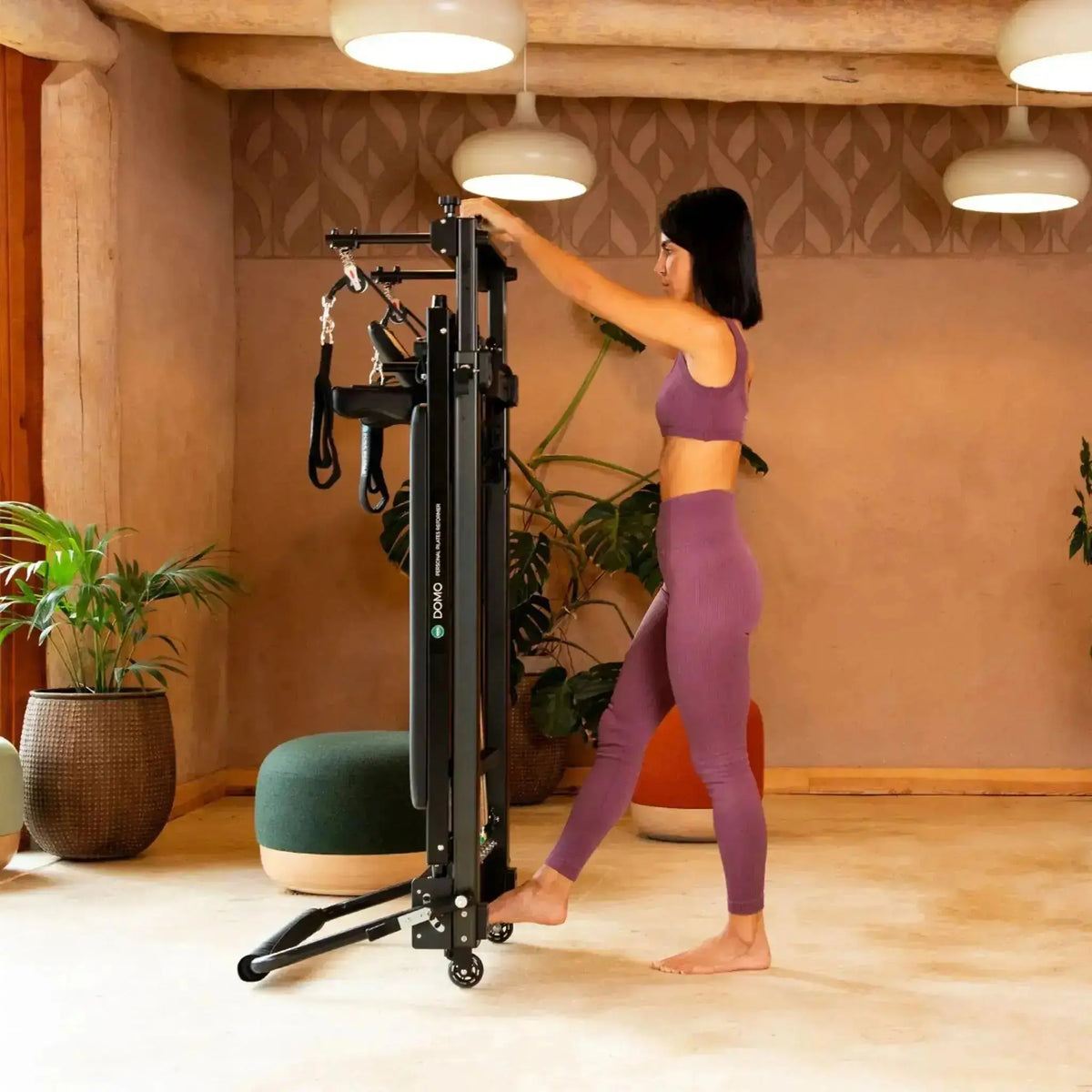 Elina Pilates Domo Reformer aus Aluminium im Studio, eine Frau stellt das Gerät senkrecht auf