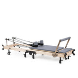 Elina Pilates Klappbarer Reformer aus Ahornholz mit grauem Polster, Seitenansicht aufgeklappt mit Seilzügen und Fußstange