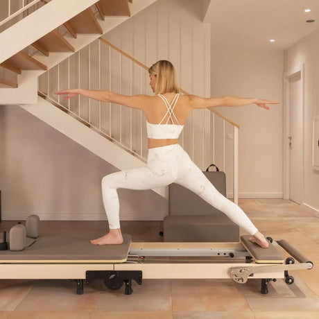 Elina Pilates Klappbarer Reformer aus Ahornholz im Wohnbereich, Frau trainiert im Ausfallschritt auf dem Wagen