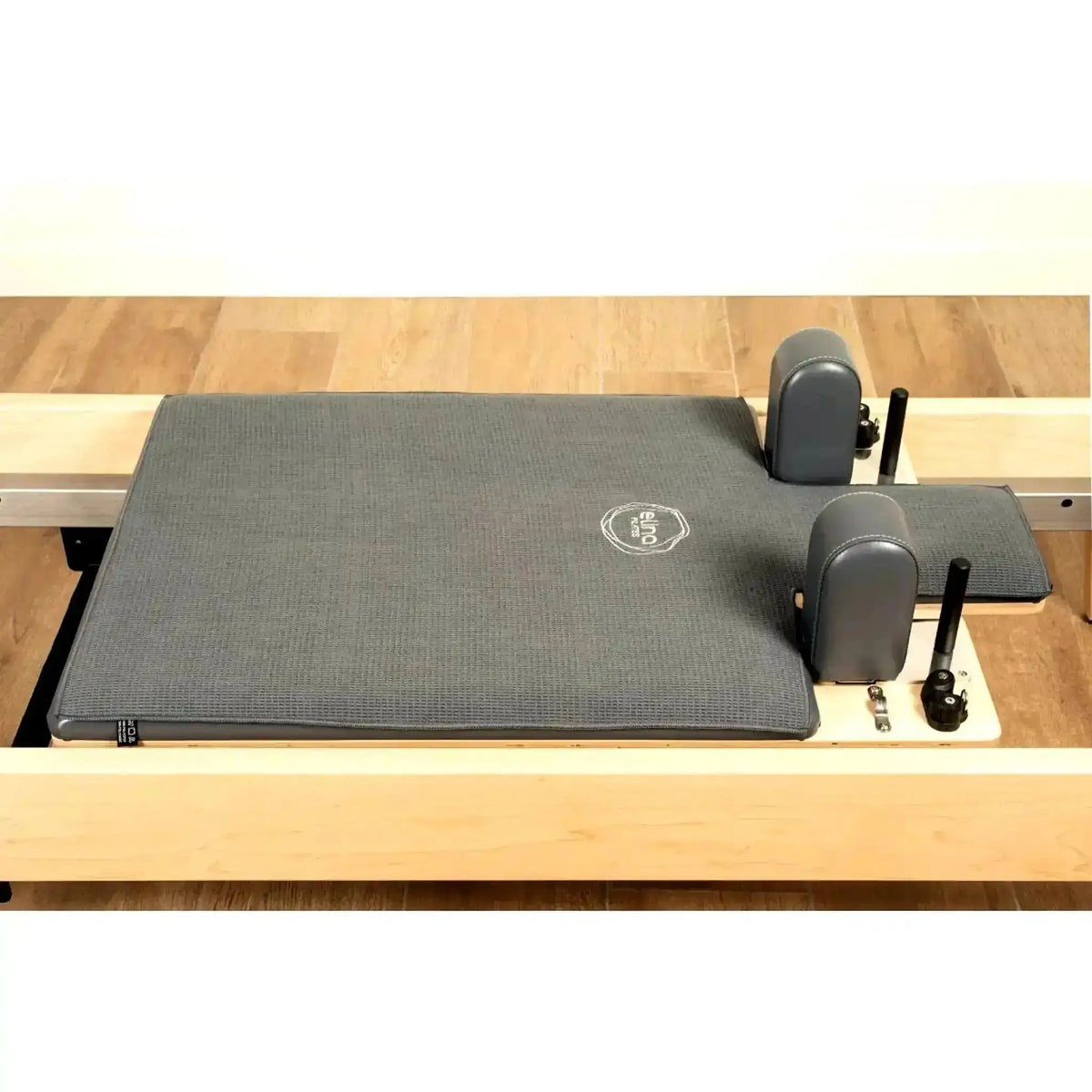 Elina Pilates Machine Towel Reformer-Handtuch in Grau auf dem Liegewagen eines Holz-Reformers, Schrägansicht mit Schulterstützen
