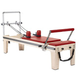 Elina Pilates Master Instructor Physio Reformer aus Ahornholz mit roten Polstern, Seitenansicht auf Weiß