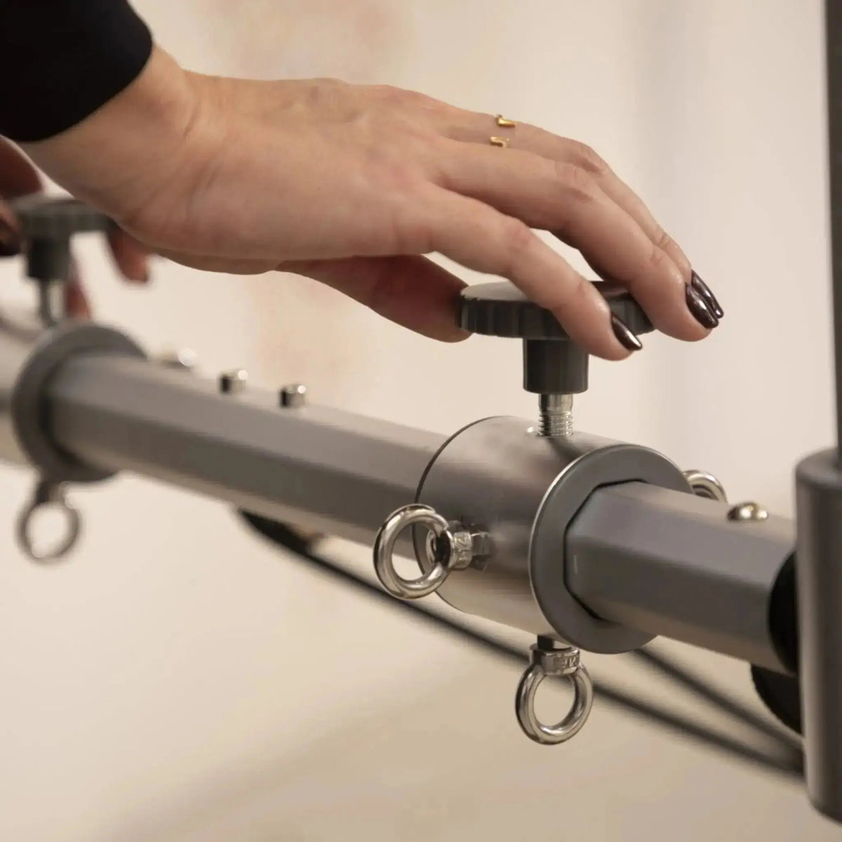 Elina Pilates Master Instructor Reformer aus Ahornholz – Detail: Hand verstellt den Klemmhebel an der Querstange