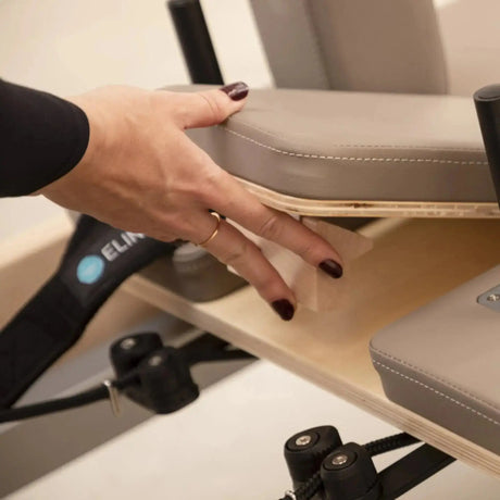 Elina Pilates Master Instructor Reformer aus Ahornholz – Detail: Hand hebt das Polster der Sitzbox an