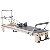Elina Pilates Master Instructor Reformer aus Ahornholz – Schrägansicht mit Polstern in Grau, freigestellt vor weißem Hintergrund