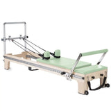 Elina Pilates Master Instructor Reformer aus Ahornholz – Schrägansicht mit Polstern in Grün, freigestellt vor weißem Hintergrund