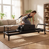 Elina Pilates Nubium Black Edition Reformer aus schwarzem Aluminium im Einsatz: Frau trainiert morgens im Wohnzimmer
