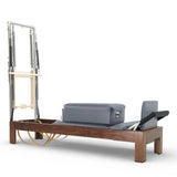 Elina Pilates Reformer Klassisch Dunkles Holz mit Tower, Schrägansicht mit grauen Polstern und dunklem Holzrahmen