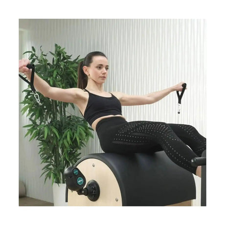 Frau trainiert mit dem Elina Pilates Training Cord Widerstandstrainer auf einem Pilates-Fass im Studio
