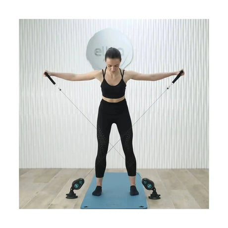 Frau steht mit seitlich gestreckten Armen und dem Elina Pilates Training Cord Widerstandstrainer