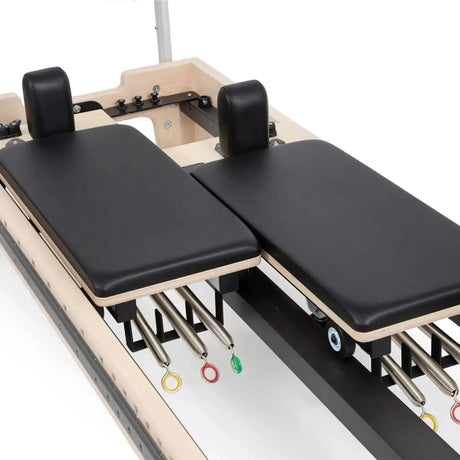 Elina Pilates Twin Reformer aus Ahornholz, Detail der beiden Wagen mit Schulterstützen und farbigen Federn
