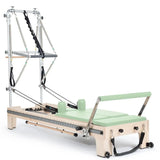 Elina Pilates Twin Reformer aus Ahornholz mit hellgrünen Polstern, Seitenansicht mit Turm auf Weiß