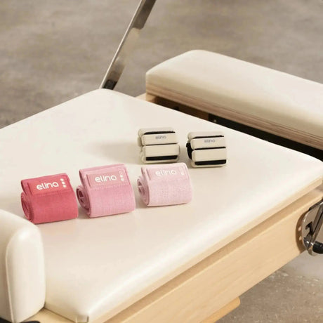Elina Pilates verstellbare Gewichte 0,5 kg für Handgelenk und Knöchel in Rosa und Beige auf einem Pilates Reformer