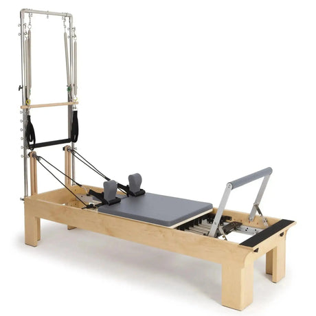 Elina Pilates Wooden Reformer Fisio mit Tower, Schrägansicht mit Polster in Grau und Holzrahmen