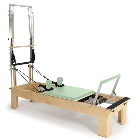 Elina Pilates Wooden Reformer Fisio mit Tower, Schrägansicht mit Polster in Grün und Holzrahmen
