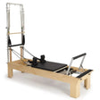 Elina Pilates Wooden Reformer Fisio mit Tower, Schrägansicht mit Polster in Schwarz und Holzrahmen