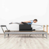Hegren Pilates Box Modern auf dem Reformer, Frau liegt bäuchlings beim Zugtraining