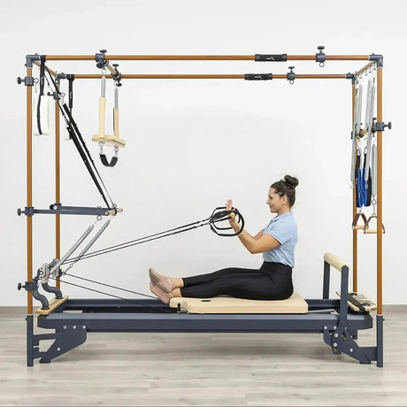 Hegren Pilates Wooden Stick 1,10 m aus Eiche, Frau sitzt auf dem Cadillac-Reformer und zieht den Stab an Seilen