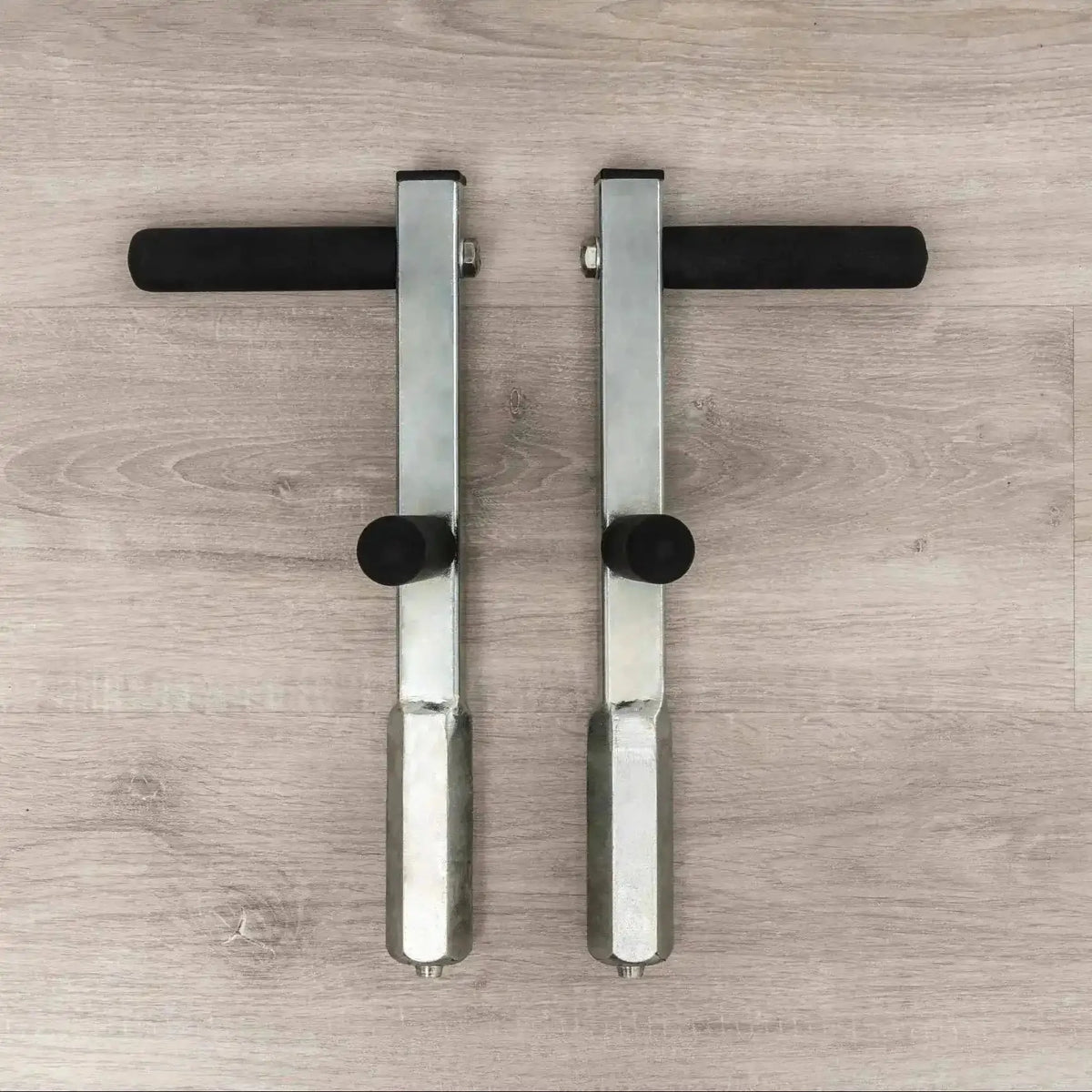 Hegren Plank Grips TALMA Reformer-Griffe als Paar von oben auf Holzboden, Metallstangen mit Schaumgriffen