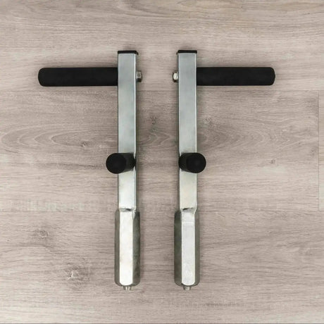 Hegren Plank Grips TALMA Reformer-Griffe als Paar von oben auf Holzboden, Metallstangen mit Schaumgriffen