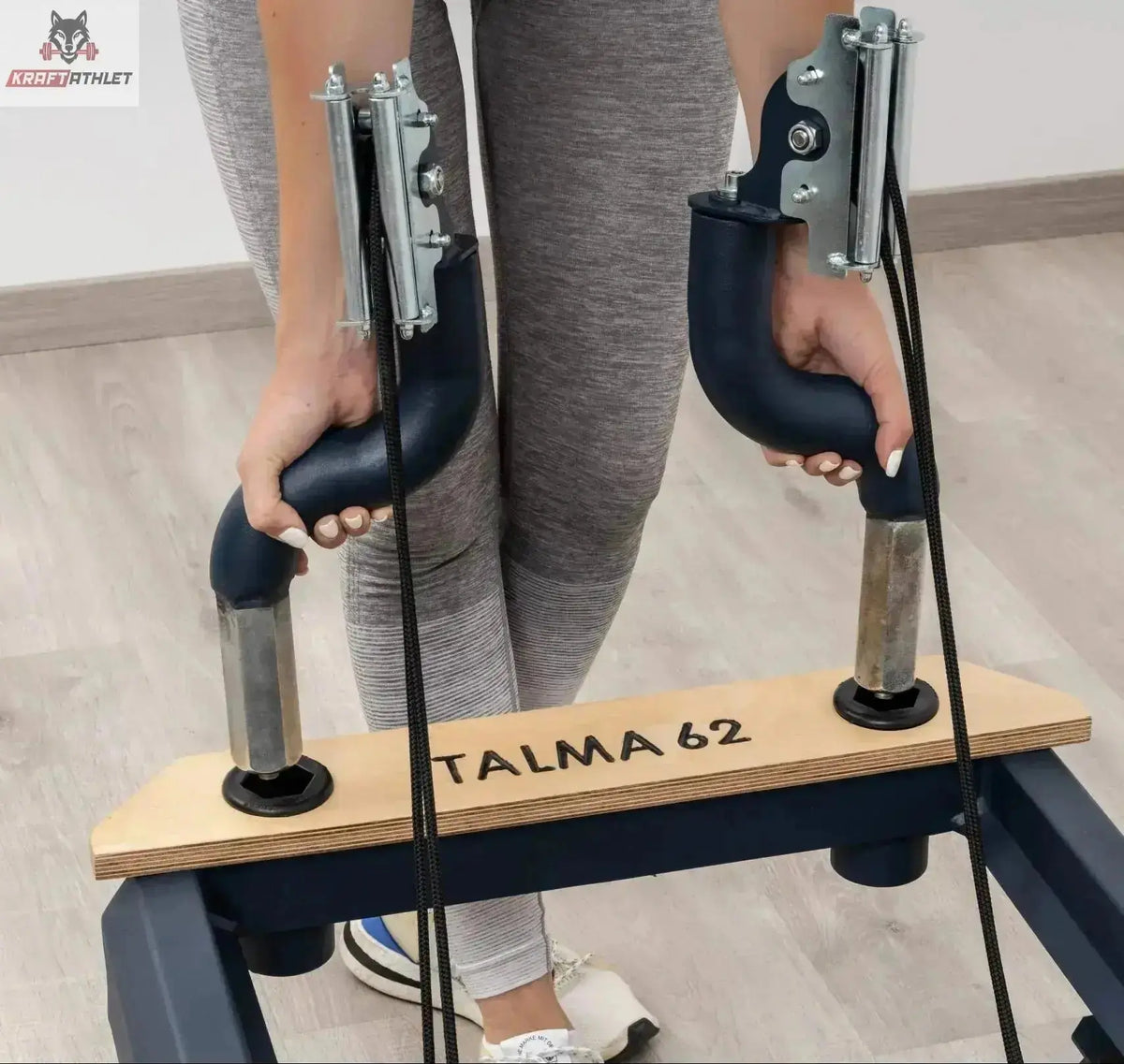 Hegren TALMA 62 Reformer mit Box und Jumpboard im Detail: Hände an den Griffen der Fußstange mit TALMA 62 Gravur