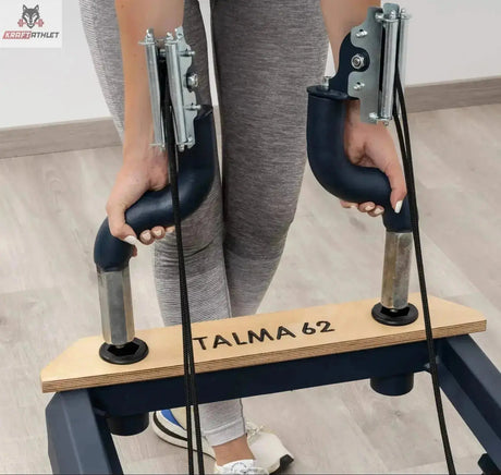 Hegren TALMA 62 Reformer mit Box und Jumpboard im Detail: Hände an den Griffen der Fußstange mit TALMA 62 Gravur