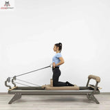Hegren TALMA 62 Reformer mit Box und Jumpboard mit Frau im Kniestand beim Seilzug-Training in Seitenansicht