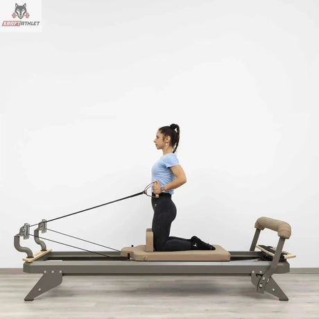 Hegren TALMA 62 Reformer mit Box und Jumpboard mit Frau im Kniestand beim Seilzug-Training in Seitenansicht