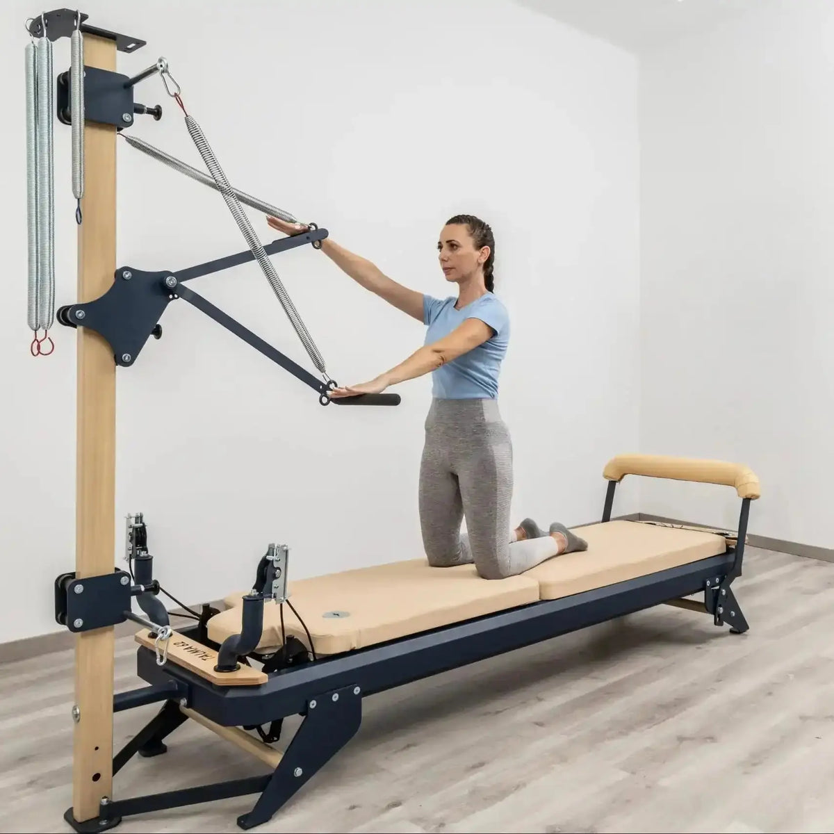 Hegren TALMA 62CT+ Reformer mit Tower, Frau kniet auf dem Schlitten und zieht die Tower-Stange