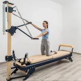 Hegren TALMA 62CT+ Reformer mit Tower, Frau kniet auf dem Schlitten und zieht die Tower-Stange