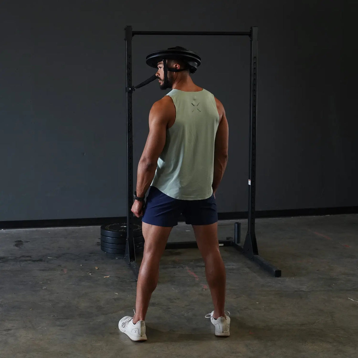 Rückansicht: Sportler trainiert mit dem Iron Neck Strength Kit Band-Set an einem Rack im Home-Gym