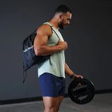 Mann mit Turnbeutel aus dem Iron Neck Strength Kit Band-Set über der Schulter, Nackentrainer in der Hand