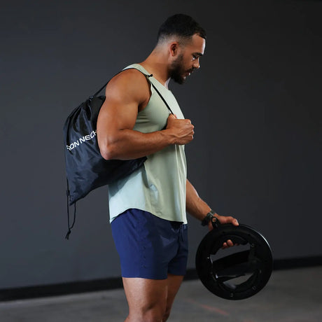 Mann mit Turnbeutel aus dem Iron Neck Strength Kit Band-Set über der Schulter, Nackentrainer in der Hand