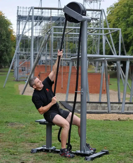 Ropeflex RX5500 Outdoor-Seiltrainer – Mann trainiert im Sitzen am Seil auf einem Outdoor-Parcours