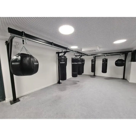 SportCom Birnenförmiger Uppercut-Sandsack Kunstleder, Reihe von Säcken an Gestellen in einem hellen Raum