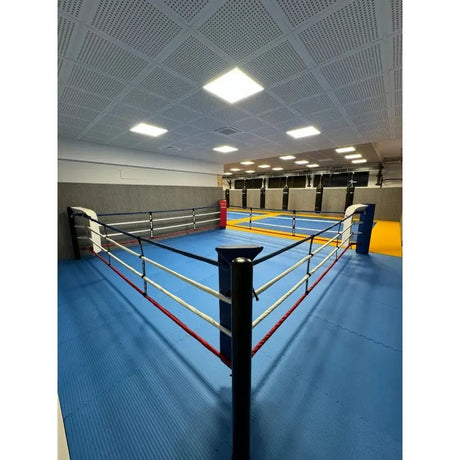 SportCom Bodenanker-Boxring mit Stahlpfosten in einer Halle mit blauem Boden, Blick vom Eckpfosten