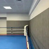SportCom Bodenanker-Boxring mit Stahlpfosten, Seilseite an der grauen Hallenwand