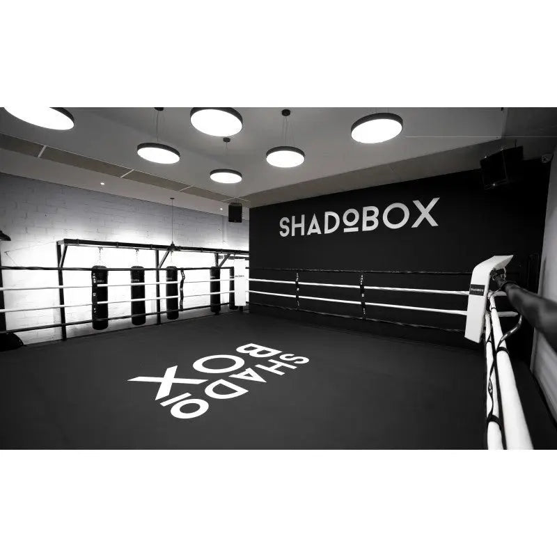 SportCom Boxring-Individualisierung: schwarzer Boden mit weißem Schriftzug und passender Wandbeschriftung