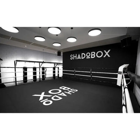 SportCom Boxring-Individualisierung: schwarzer Boden mit weißem Schriftzug und passender Wandbeschriftung