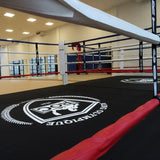 SportCom Boxring-Individualisierung: Detail des Ringbodens mit rundem Logo und roter Seilummantelung