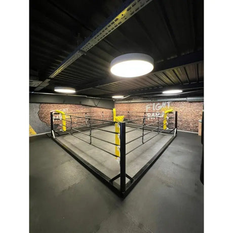 SportCom Boxring-Individualisierung: Bodenring mit gelben Eckpolstern in einer Halle mit Deckenleuchte