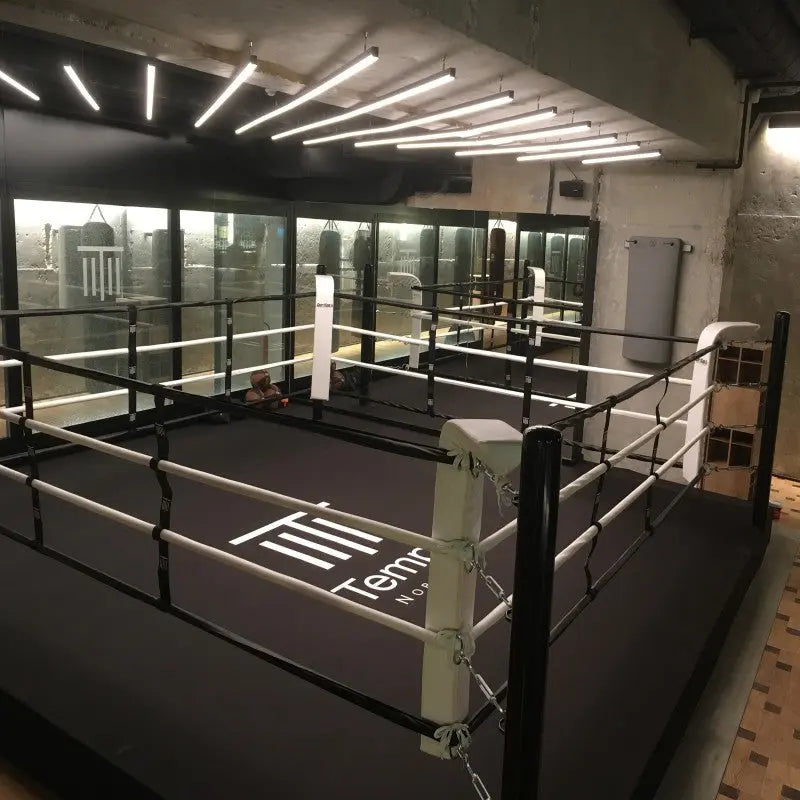 SportCom Boxring-Individualisierung: schwarzer Ring mit weißen Ecken und Logo in einem Studio mit Glasfront