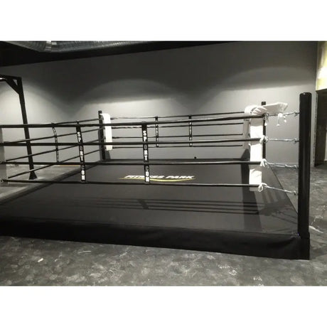 SportCom Boxring-Seiltrenner 8er-Set an einem schwarzen Boxring in einer leeren grauen Halle
