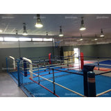 SportCom Doppel-Boxring mit Spannseilen und Stahlpfosten, in einer Halle mit roten und blauen Ecken, schräg