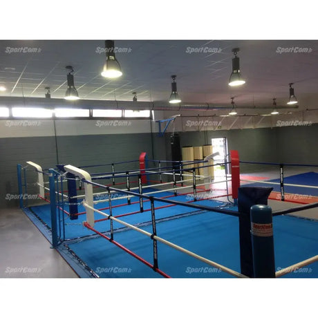 SportCom Doppel-Boxring mit Spannseilen und Stahlpfosten, in einer Halle mit roten und blauen Ecken, schräg