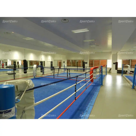 SportCom Doppel-Boxring mit Spannseilen und Stahlpfosten, in einer Halle mit Spiegelwand und blauem Boden