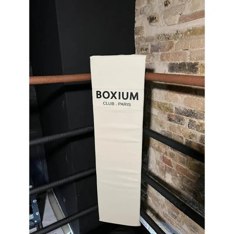 SportCom Eckpolster-Set für Boxringe mit 4 Seilen, weißes Polster mit Clublogo an einer Ringecke vor Backsteinwand