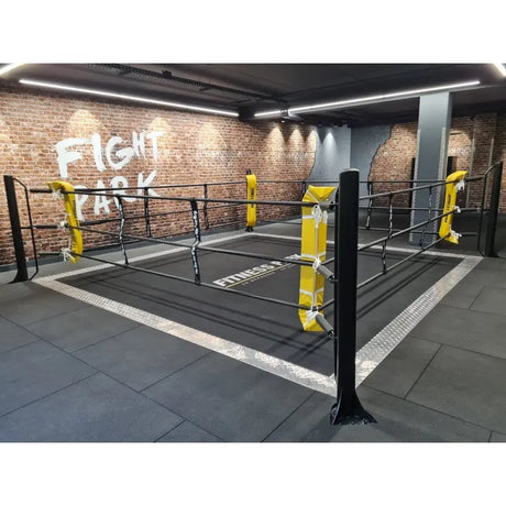 SportCom Ecofix Bodenmontage-Boxring mit Aluminiumrand, vor Backsteinwand mit gelben Polstern und weißem Rand