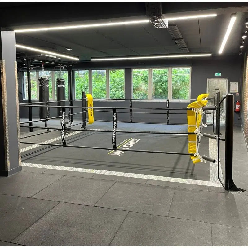 SportCom Ecofix Bodenmontage-Boxring mit Aluminiumrand, in einem Gym mit Fensterfront und gelben Polstern