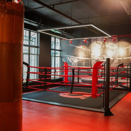 SportCom Ecofix Bodenmontage-Boxring mit Aluminiumrand, in einem Gym mit rotem Boden und Lichtrahmen