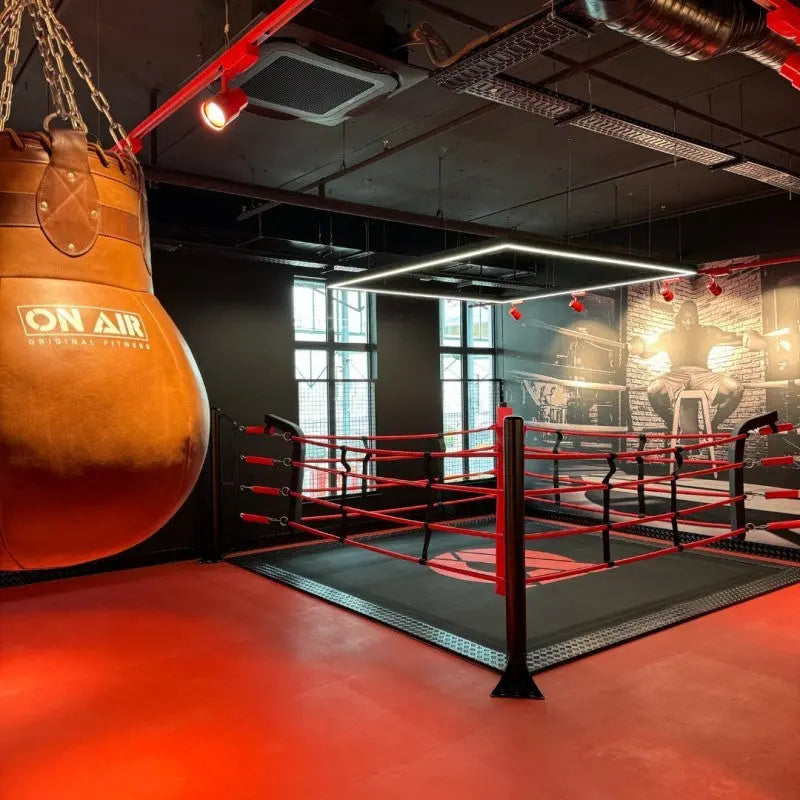 SportCom Ecofix Bodenmontage-Boxring mit Aluminiumrand, mit Sandsack im Vordergrund und rotem Boden